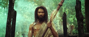 Movie still from “Ong Bak 3” (2010), directed by Tony Jaa – A man with long hair and a beard holding a spear; Medium shot, Low angle
