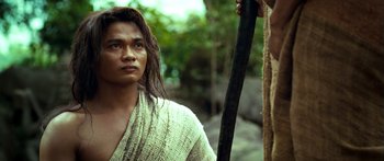 Movie still from “Ong Bak 3” (2010), directed by Tony Jaa – A man in a white robe holding a black stick; Close Up shot, Low angle