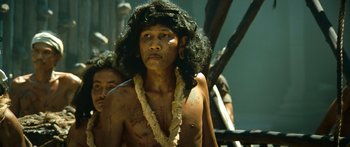 Movie still from “Ong Bak 3” (2010), directed by Tony Jaa – A man with long black hair wearing a necklace; Close Up shot, Low angle