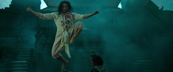Movie still from “Ong Bak 3” (2010), directed by Tony Jaa – A man is jumping in the air while another man watches; Medium shot, Low angle