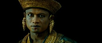 Movie still from “Ong Bak 3” (2010), directed by Tony Jaa – A person wearing a gold hat; Close Up shot, Low angle