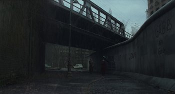 Movie still from “Suspiria” (2018), directed by Luca Guadagnino – Two people standing under a bridge near a fire hydrant; Extreme Wide shot, High angle