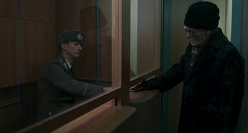 Movie still from “Suspiria” (2018), directed by Luca Guadagnino – A man in black jacket standing next to a man in a military uniform; Medium shot, Over the shoulder angle