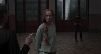 Movie still from “Suspiria” (2018), directed by Luca Guadagnino – A woman with red hair is smoking a cigarette; Medium shot, Over the shoulder angle