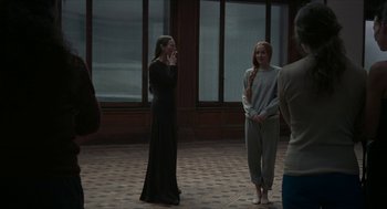 Movie still from “Suspiria” (2018), directed by Luca Guadagnino – A group of people standing around in a room; Wide shot, Over the shoulder angle