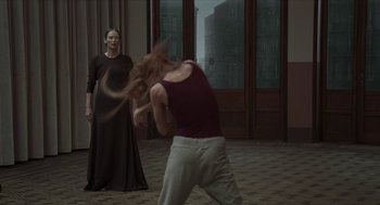 Movie still from “Suspiria” (2018), directed by Luca Guadagnino – A woman in a black dress and a woman in a black dress; Medium shot, Over the shoulder angle
