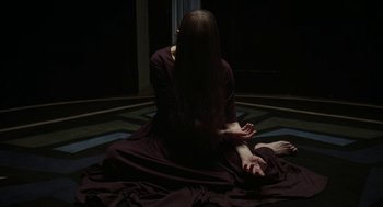 Movie still from “Suspiria” (2018), directed by Luca Guadagnino – A woman sitting on the ground in a dark room; Medium shot, High angle
