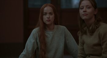 Movie still from “Suspiria” (2018), directed by Luca Guadagnino – A woman with long red hair is looking at the camera; Medium shot, Over the shoulder angle