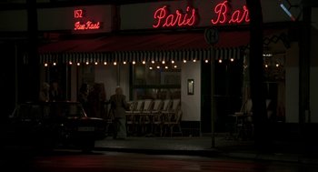 Movie still from “Suspiria” (2018), directed by Luca Guadagnino – A person standing in front of a restaurant at night; Wide shot, Over the shoulder angle