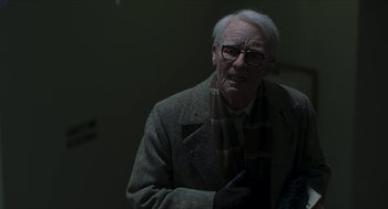 Movie still from “Suspiria” (2018), directed by Luca Guadagnino – An older man wearing a coat and a scarf; Close Up shot, Over the shoulder angle