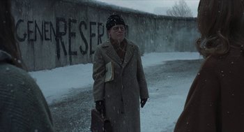 Movie still from “Suspiria” (2018), directed by Luca Guadagnino – An old man walking in the snow holding a briefcase; Medium shot, Over the shoulder angle