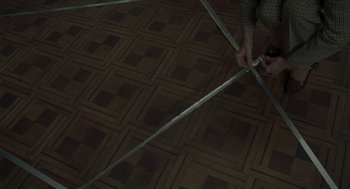 Movie still from “Suspiria” (2018), directed by Luca Guadagnino – A person is holding a measuring tape on the floor; Wide shot, Overhead angle