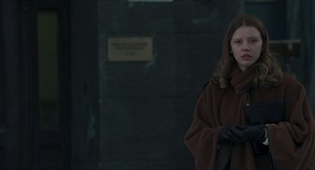Movie still from “Suspiria” (2018), directed by Luca Guadagnino – A woman in a brown coat holding a black purse; Medium shot, Low angle