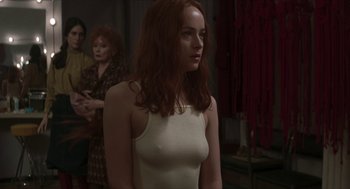 Movie still from “Suspiria” (2018), directed by Luca Guadagnino – A woman with long red hair standing in a room; Medium shot, Over the shoulder angle