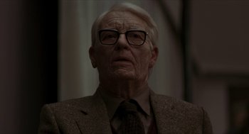 Movie still from “Suspiria” (2018), directed by Luca Guadagnino – An old man wearing glasses and a suit; Close Up shot, Over the shoulder angle