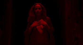 Movie still from “Suspiria” (2018), directed by Luca Guadagnino – A woman with her hands over her chest; Medium shot, Overhead angle