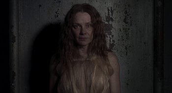 Movie still from “Suspiria” (2018), directed by Luca Guadagnino – A woman with long brown hair standing in front of a wall; Close Up shot, Low angle