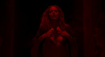 Movie still from “Suspiria” (2018), directed by Luca Guadagnino – A woman in a black dress holding her hands over her chest; Medium shot, Overhead angle