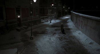Movie still from “Suspiria” (2018), directed by Luca Guadagnino – A person walking down a snowy street at night; Extreme Wide shot, High angle