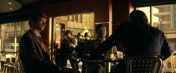 Movie still from “Swordfish” (2001), directed by Dominic Sena – A group of men standing around a table with cups; Medium shot, Over the shoulder angle