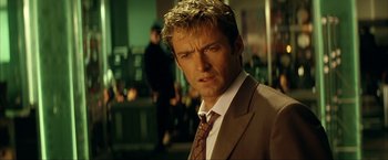 Movie still from “Swordfish” (2001), directed by Dominic Sena – A man in a brown suit and a brown tie; Close Up shot, Low angle