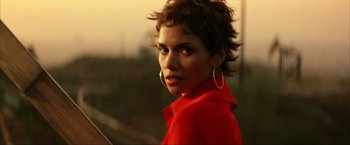 Movie still from “Swordfish” (2001), directed by Dominic Sena – A woman in a red shirt is looking at the camera; Close Up shot, Over the shoulder angle