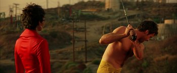Movie still from “Swordfish” (2001), directed by Dominic Sena – A man is holding his arm up in the air; Medium shot, Low angle