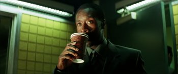 Movie still from “Swordfish” (2001), directed by Dominic Sena – A man in a suit and tie holding a cup of coffee; Close Up shot, High angle