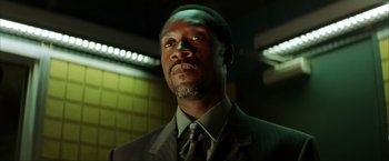 Movie still from “Swordfish” (2001), directed by Dominic Sena – A man wearing a suit and tie in a dark room; Close Up shot, Low angle