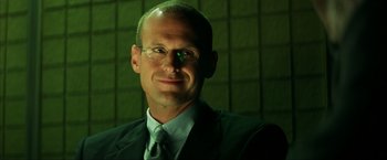 Movie still from “Swordfish” (2001), directed by Dominic Sena – A person wearing a suit and glasses; Close Up shot, Low angle