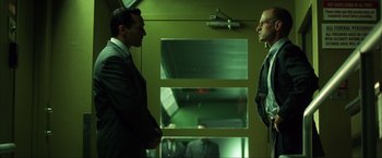 Movie still from “Swordfish” (2001), directed by Dominic Sena – Two men in suits are talking in a room; Medium shot, Low angle