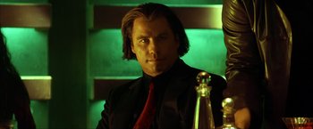 Movie still from “Swordfish” (2001), directed by Dominic Sena – A man in a black suit and red neck tie; Close Up shot, Low angle