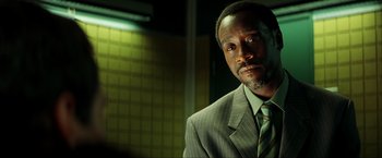 Movie still from “Swordfish” (2001), directed by Dominic Sena – A man wearing a suit and tie in front of a wall; Close Up shot, Low angle