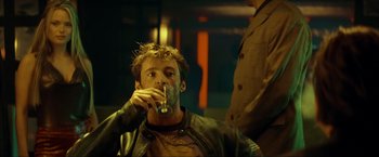 Movie still from “Swordfish” (2001), directed by Dominic Sena – A man drinking a drink from a glass in front of another man; Close Up shot, Low angle