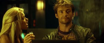 Movie still from “Swordfish” (2001), directed by Dominic Sena – A person sitting at a table holding a drink; Close Up shot, Over the shoulder angle