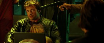 Movie still from “Swordfish” (2001), directed by Dominic Sena – A man with a gun on his head and a laptop in front of him; Medium shot, Over the shoulder angle