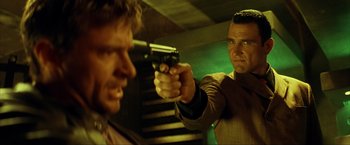 Movie still from “Swordfish” (2001), directed by Dominic Sena – A man holding a gun pointed at another man with a gun; Close Up shot, Low angle