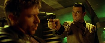 Movie still from “Swordfish” (2001), directed by Dominic Sena – A man holding a gun pointed at another man with a gun; Close Up shot, Low angle