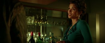Movie still from “Swordfish” (2001), directed by Dominic Sena – A woman standing in front of a bar with wine bottles; Close Up shot, Over the shoulder angle