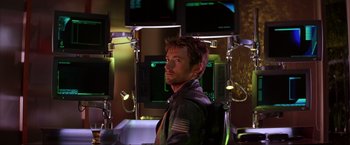 Movie still from “Swordfish” (2001), directed by Dominic Sena – A man standing in front of a bunch of computer monitors; Medium shot, Low angle