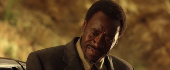 Movie still from “Swordfish” (2001), directed by Dominic Sena – A man in a suit and tie looking sad; Close Up shot, Over the shoulder angle