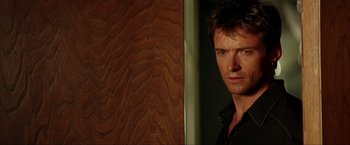 Movie still from “Swordfish” (2001), directed by Dominic Sena – A person standing next to a wooden wall; Close Up shot, Over the shoulder angle