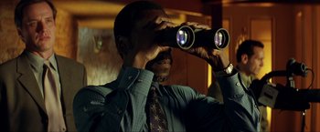 Movie still from “Swordfish” (2001), directed by Dominic Sena – A man looking through binoculars while wearing a tie; Close Up shot, Low angle