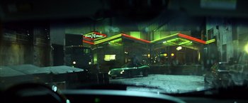 Movie still from “Swordfish” (2001), directed by Dominic Sena – A car parked in front of a gas station at night; Wide shot, Over the shoulder angle