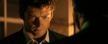 Movie still from “Swordfish” (2001), directed by Dominic Sena – A person wearing a suit and tie; Close Up shot, Over the shoulder angle