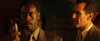 Movie still from “Swordfish” (2001), directed by Dominic Sena – A person wearing a suit and tie; Close Up shot, Low angle