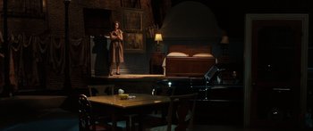 Movie still from “Synecdoche, New York” (2008), directed by Charlie Kaufman – A woman standing in a room next to a bed and a table; Wide shot, High angle