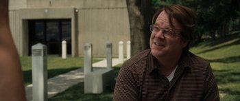 Movie still from “Synecdoche, New York” (2008), directed by Charlie Kaufman – A man sitting in the grass wearing glasses; Close Up shot, Over the shoulder angle