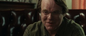 Movie still from “Synecdoche, New York” (2008), directed by Charlie Kaufman – A person wearing glasses and smiling; Close Up shot, Over the shoulder angle