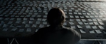 Movie still from “Synecdoche, New York” (2008), directed by Charlie Kaufman – A person sitting in front of a wall of papers; Medium shot, Over the shoulder angle